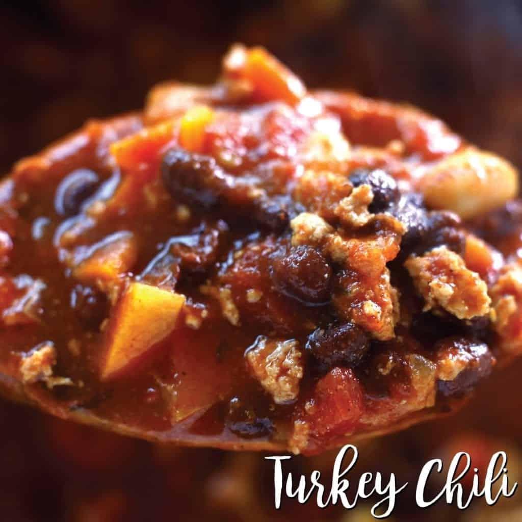 up close wood spoon shot of turkey chili with black beans, carrots, onion and cannellini beans #instantpotchili #turkeychili #easyrecipes #dinner #healthycomfortfood #bingeworthybites #recipe