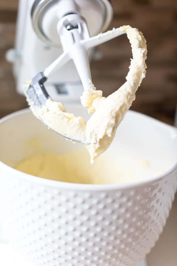 up close picture of soft sugar cookie dough consistency like a thick batter in white Kitchenaid stand mixer #sugarcookies #lofthousecookiedupe #softsugarcookies #frostedsugarcookie #homemadefrosting #dessert #baking #easyrecipes #bingeworthybites #homemadecookierecipes #bestcookierecipes #softestsugarcookies