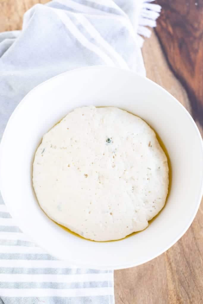 Garlic Herb Pita Bread dough in white mixing bowl after proofing and doubling in size
