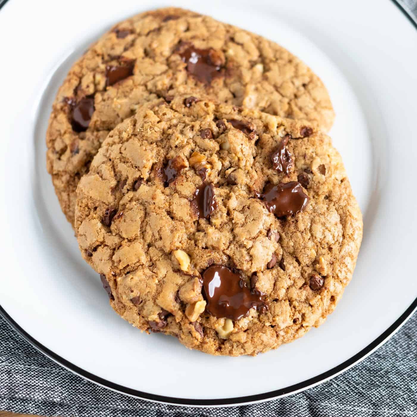 up close picture of DoubleTree's Signature Chocolate Chip Cookies on white dish with black rim on denim napkin #cookie #chocolatechipcookie #doubletreesignaturecookie #baking
