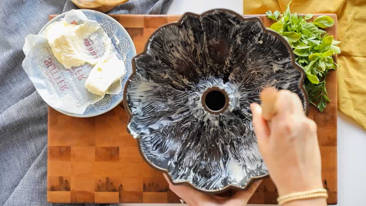 Coating a Nordicware bundt pan with butter using a pastry brush. 